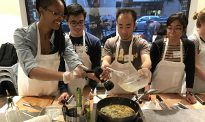 4 students cooking a dish together in the kitchen