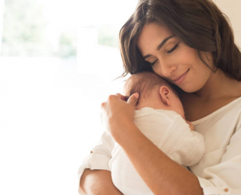 Pretty woman holding a newborn baby in her arms.