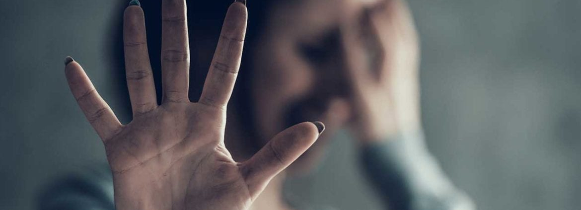 A woman holding her hand up to block camera.