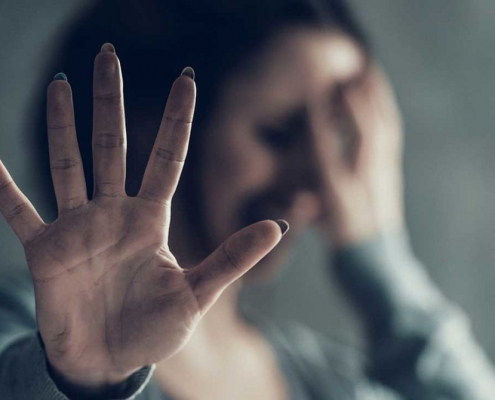 A woman holding her hand up to block camera.