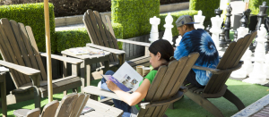 2 people sitting outside relaxing and reading a magazine