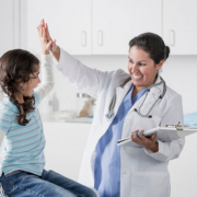 a doctor giving a girl a high five during her doctor visit