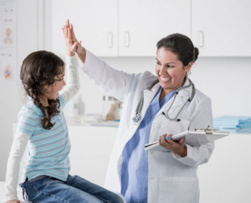 a doctor giving a girl a high five during her doctor visit