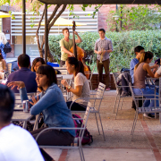 People talking at the tables outside and a person playing music