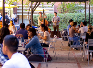 People talking at the tables outside and a person playing music