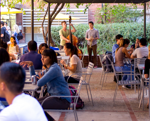 People talking at the tables outside and a person playing music