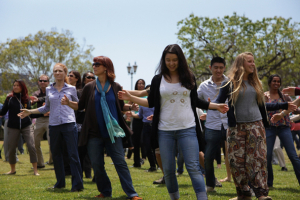 A group of people dancing on grass outside