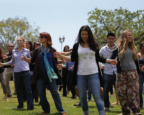 A group of people dancing on grass outside