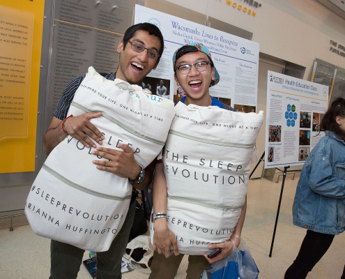 two students holding pillows posing for a picture