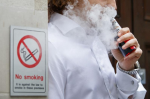 someone vaping in front of a no smoking sign