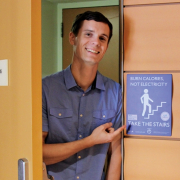 a man pointing to a sign about how people should take the stairs to burn calories