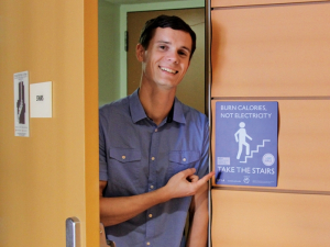 a man pointing to a sign about how people should take the stairs to burn calories