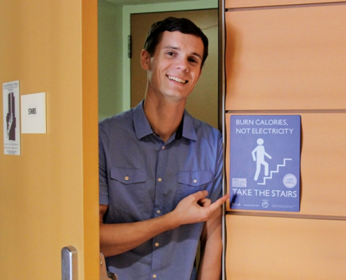 a man pointing to a sign about how people should take the stairs to burn calories