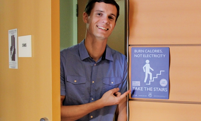 a man pointing to a sign about how people should take the stairs to burn calories