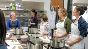 4 women at the UCLA test kitchen listening to a woman instructor teach a cooking class