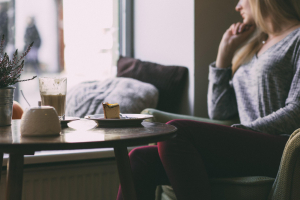 woman sitting at a cafe with cheesecake and coffee