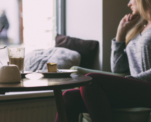 woman sitting at a cafe with cheesecake and coffee