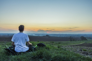 man meditating on a field