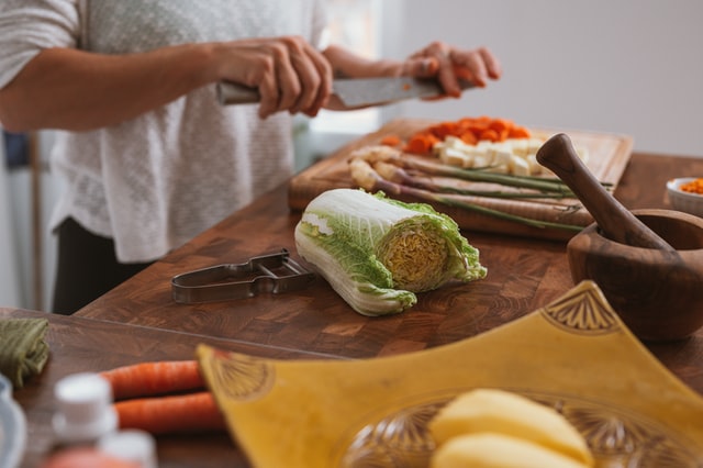 Person cooking- chopping carrots and napa cabbage